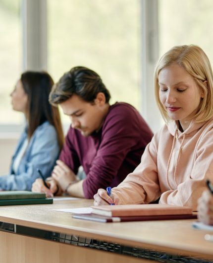 Female university student writing an exam in the classroom.