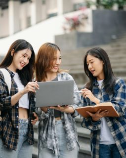 Three young Asian college students and a female student group work at the campus park